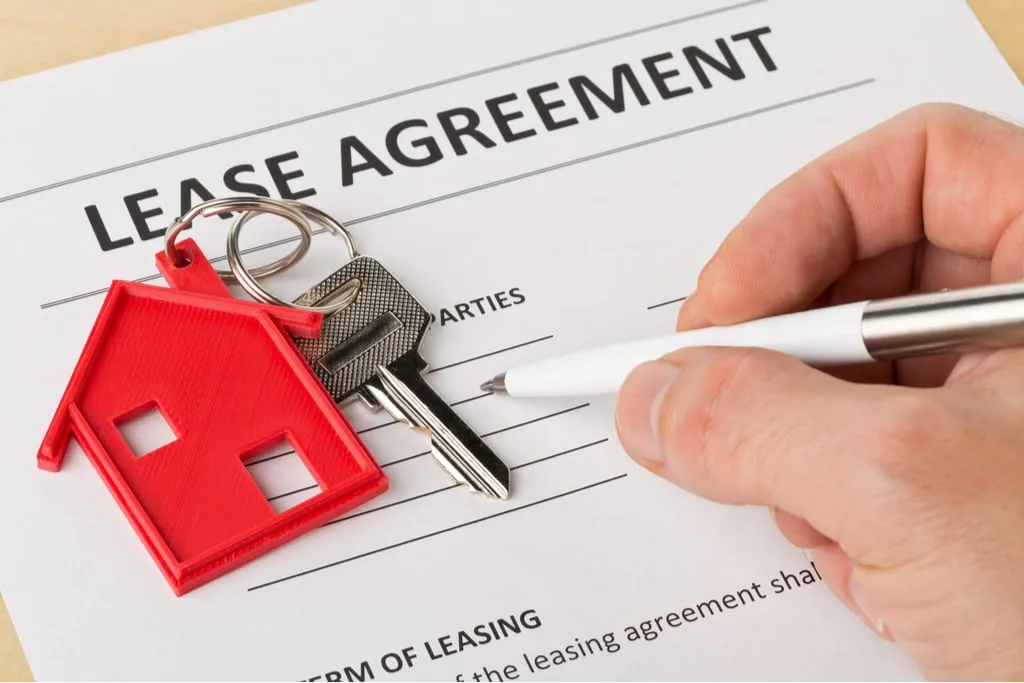 A lease agreement being signed, with house keys on top